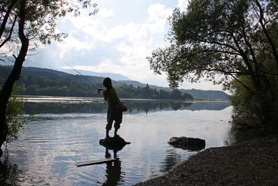 Woman standing by lake against sky