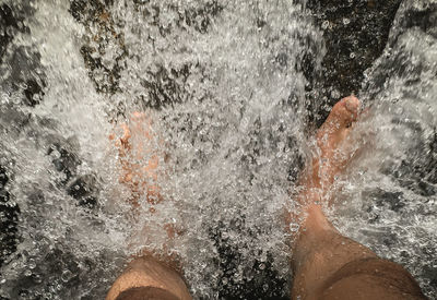 Low section of man splashing water in sea