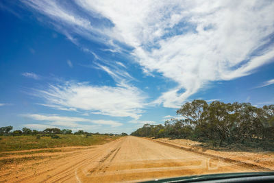 Road amidst field against sky