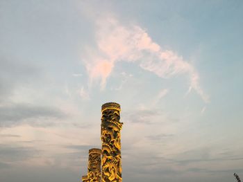 Low angle view of carved columns against sky during sunset