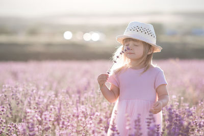 Cute girl smelling flower in field