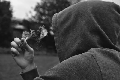 Person wearing hood while smoking outdoors