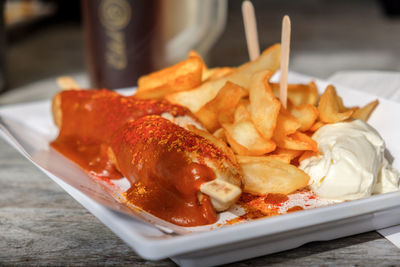 Close-up of currywurst with french fries on plate served on table