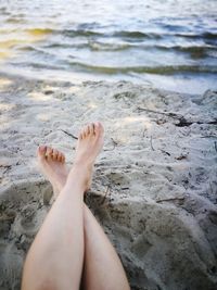 Low section of woman relaxing at beach