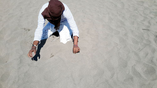 Unrecognizable person kneeling on sand