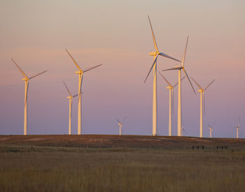 Wind turbines in field against sunset sky