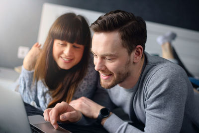 Smiling couple looking at laptop while sitting on sofa