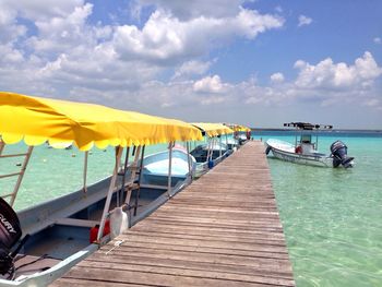 Boats moored by jetty in sea against sky