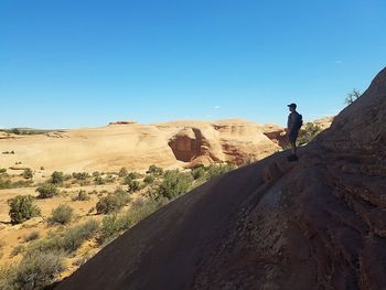 Man on rock against clear sky