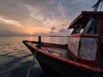 Boat moored in sea against sky during sunset