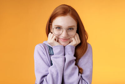 Portrait of a smiling young woman against yellow background