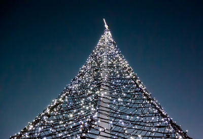 Low angle view of illuminated christmas tree against clear sky at night