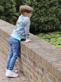 Side view of boy standing against wall