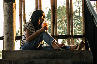 Thoughtful woman having drink while sitting on steps