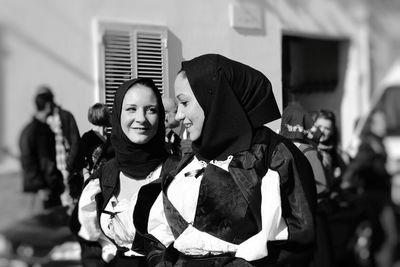 Smiling women in traditional clothing talking on city street