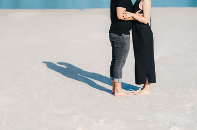 Low section of couple standing at beach