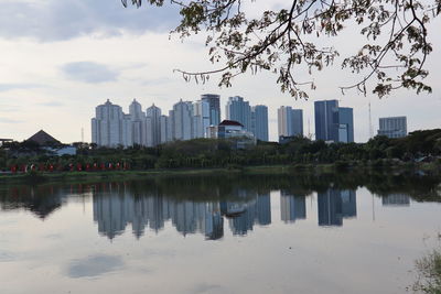 Buildings by lake against sky in city