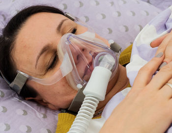 Close-up of female patient with oxygen mask sleeping on bed