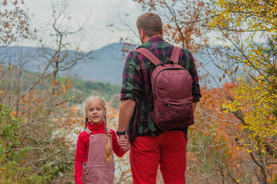 Little girl daughter goes with dad on a hike in the autumn forest