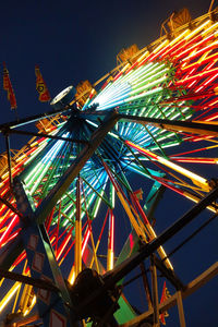 Low angle view of illuminated ferris wheel against sky at night