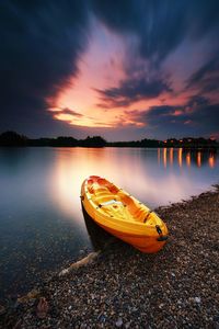 View of canoe on lakeshore at sunset