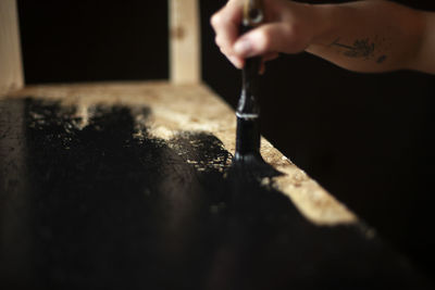 A girl paints furniture. black paint in the interior design. the curly-haired girl holds a brush.