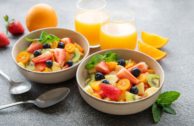Healthy fresh fruit salad in a bowl on concrete background