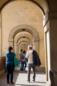 Rear view of people walking in corridor of building
