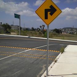 Road sign on road against sky