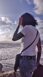 Rear view of woman standing by sea against sky