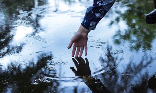 Cropped hand touching water