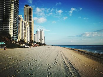 Panoramic view of beach and buildings against blue sky