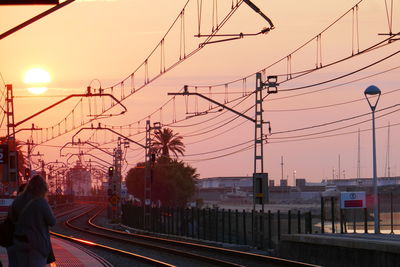 Railroad tracks in city against sky during sunset