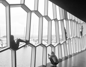 Boy standing by window against sky