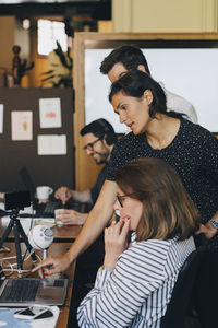 Mid adult businesswoman discussing with team over laptop in office