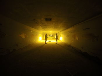 Side view of two silhouette people standing in tunnel