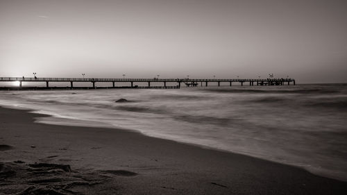 Pier on beach against clear sky