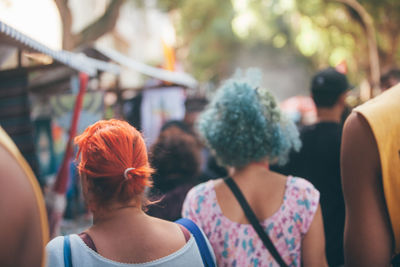 Two women with red and blue hair walking in a market
