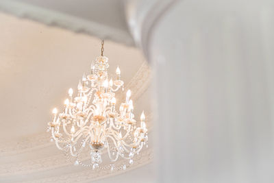 Low angle view of illuminated chandelier hanging on ceiling