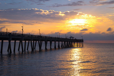 Pier over sea against sky during sunset