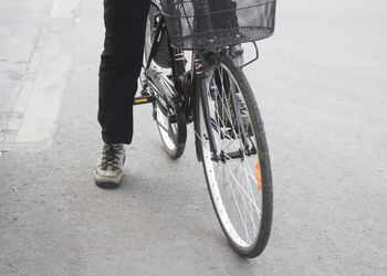 Low section of man with bicycle walking on road