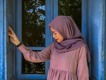 Midsection of woman standing against window