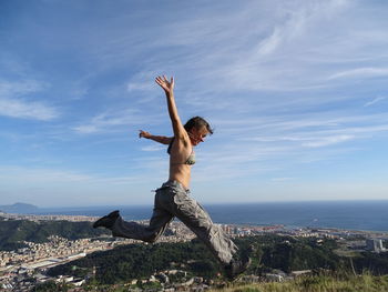 Energetic woman leaping in mid-air against sky