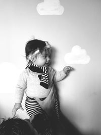 Girl looking away while standing against wall