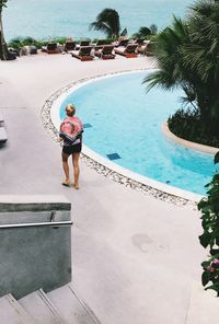 Rear view of woman walking by swimming pool