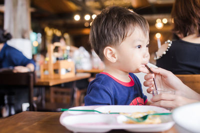 Cute baby boy having meal at restaurant