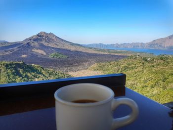 Coffee cup on mountain against blue sky