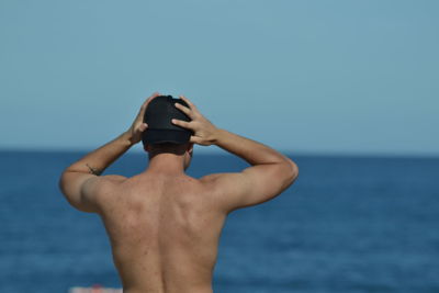 Midsection of shirtless man against sea against sky