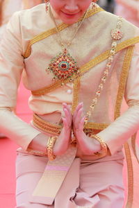 Midsection of woman holding pink while standing on hand