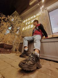 Low angle view of man sitting against wall in building